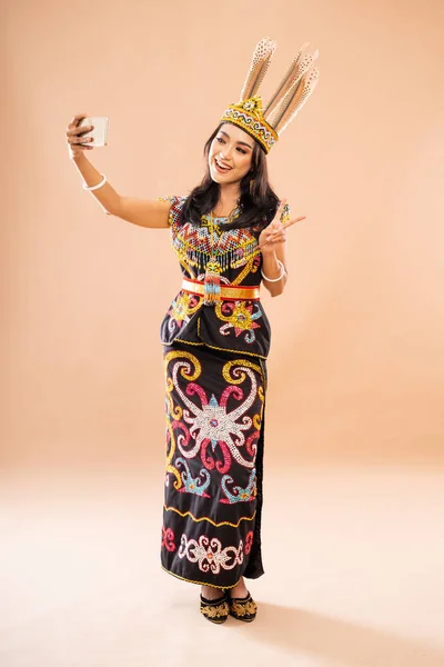 亚洲女人穿着王袍站在那里 手握和平的手势 在孤立的背景下 用手机拍照 — 图库照片