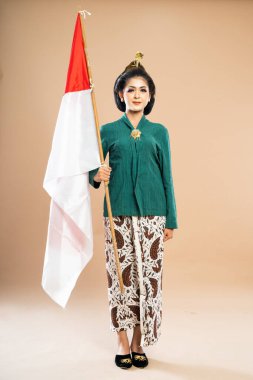 Yeşil kebaya giyen Asyalı kadın izole edilmiş arka planda Endonezya bayrağını getir.