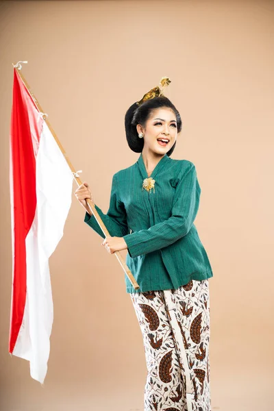 Azjatycka Kobieta Zielonej Kebaya Stojąc Trzymając Indonezyjską Flagę Obiema Rękami — Zdjęcie stockowe