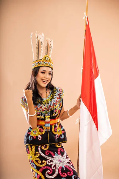 アジア系の女性は孤立した背景の上にインドネシアの国旗を掲げながら腕を食いしばっている — ストック写真