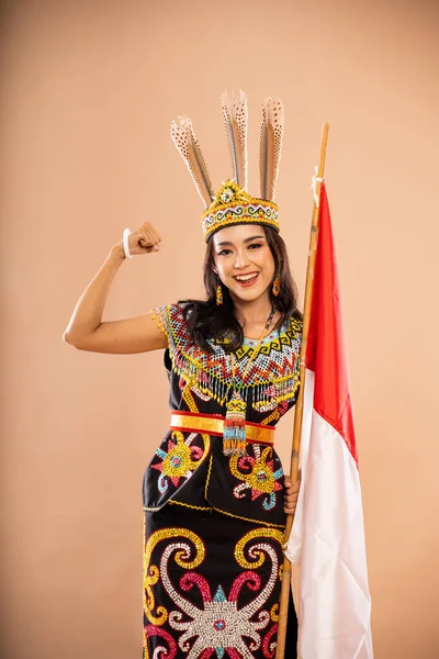 アジアの女性はインドネシアの国旗を背景に隔離された状態で笑顔と握りしめられた腕で立っている — ストック写真