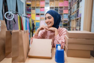 Çekici Müslüman kadın malını göndermeden önce paketledikten sonra masasında oturuyor.