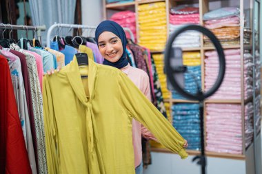 Çekici Müslüman kadın moda ürünlerini değerlendiriyor ve dükkanından sosyal medyada canlı satış yapıyor.
