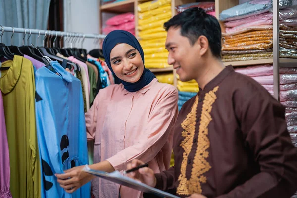 アジア系イスラム教徒の女性と男性がファッション商品をチェックしています — ストック写真