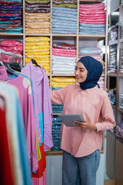 快乐微笑的穆斯林妇女在她的时装店检查产品 — 图库照片