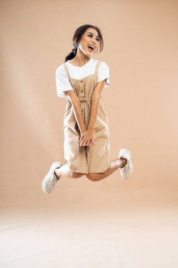 Mutlu Asyalı kadın gündelik giysiler içinde at kuyruğu ile izole edilmiş arka planda atlıyor.