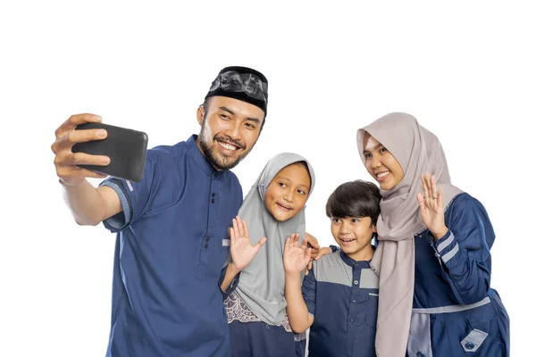 幸せなイスラム教徒の家族はビデオ通話や自撮りをしながら携帯電話に手を振って — ストック写真