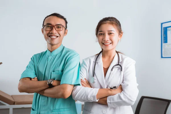一个戴着眼镜的男护士站在女医生旁边 双手交叉 面带微笑 — 图库照片