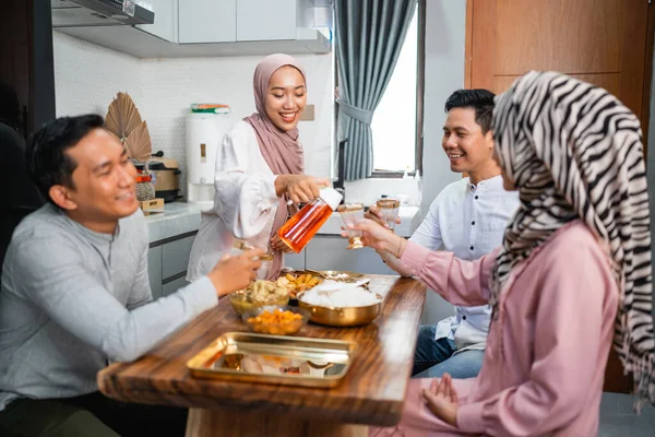 Muzułmanka Serwująca Drinka Dla Przyjaciółki Rodziny Domu Jedzącej Razem Kolację — Zdjęcie stockowe