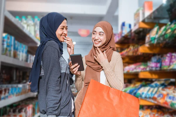 Двоє Мусульманських Дівчат Сміються Коли Користуються Смартфоном Під Час Купівлі — стокове фото