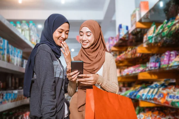 Zwei Muslimische Mädchen Beim Gemeinsamen Einkaufen Supermarkt Mit Einem Smartphone — Stockfoto