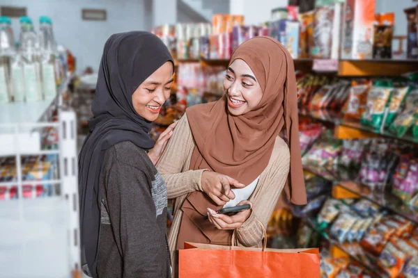 Duas Belas Meninas Muçulmanas Usando Smartphone Enquanto Fazem Compras Juntas — Fotografia de Stock