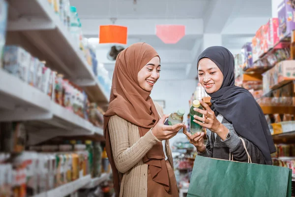 两个穆斯林女孩一边聊天一边在超市里拿着酒瓶 — 图库照片