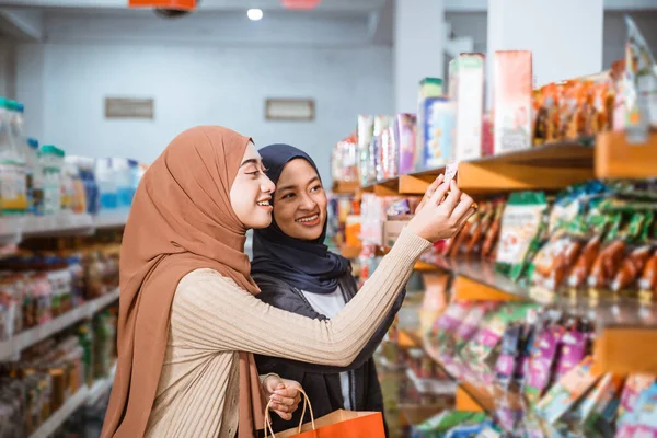 两名穆斯林女孩在超级市场购物时观察商品的价格 — 图库照片