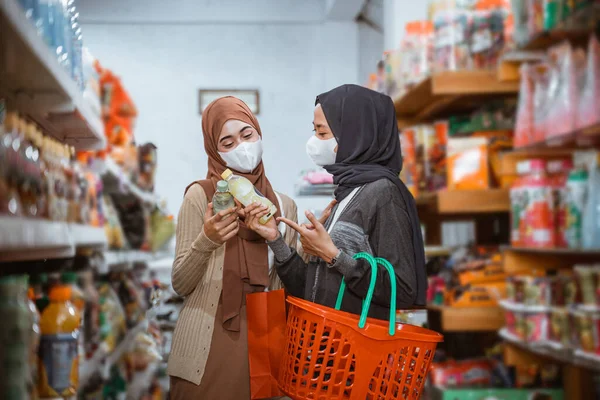 两名戴口罩的穆斯林女孩在一家商店里一起购物时观察物品 — 图库照片