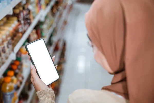 在超市购物时 戴头巾的女人用智能手机购物 — 图库照片