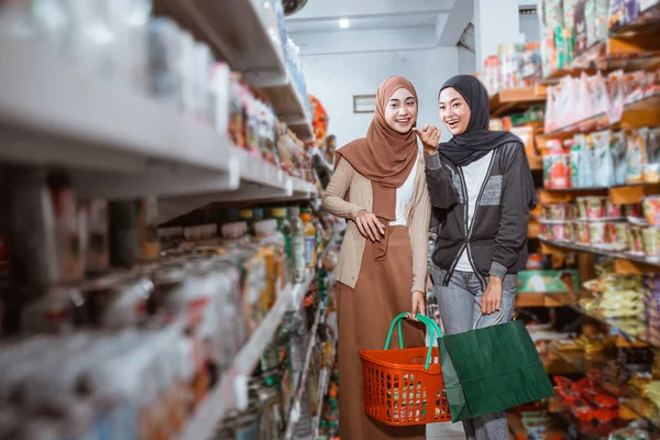 Dvě Muslimské Ženy Ukazováčkem Při Výběru Nákupních Položek Supermarketu — Stock fotografie