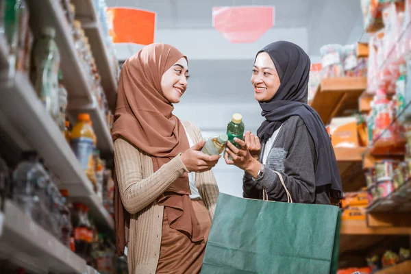 两个穆斯林女人一边聊天一边在超市里拿着酒瓶 — 图库照片