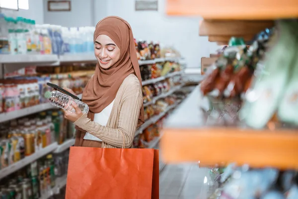穆斯林妇女在超级市场购物时手持智能手机和酒瓶 — 图库照片