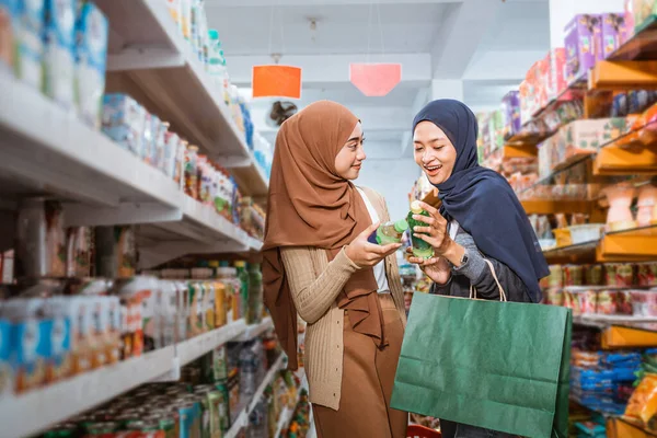 穆斯林女孩在超级市场与朋友购物时 拒绝拿起架子上的东西 — 图库照片