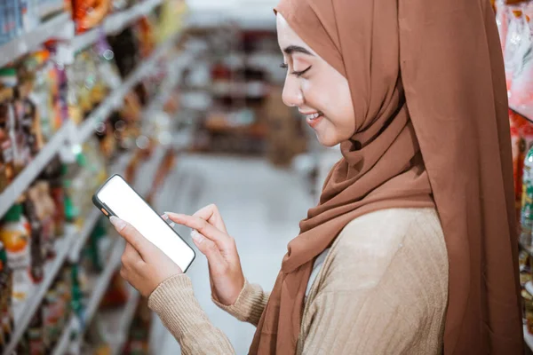 Mulher Muçulmana Usando Smartphone Enquanto Faz Compras Supermercado — Fotografia de Stock