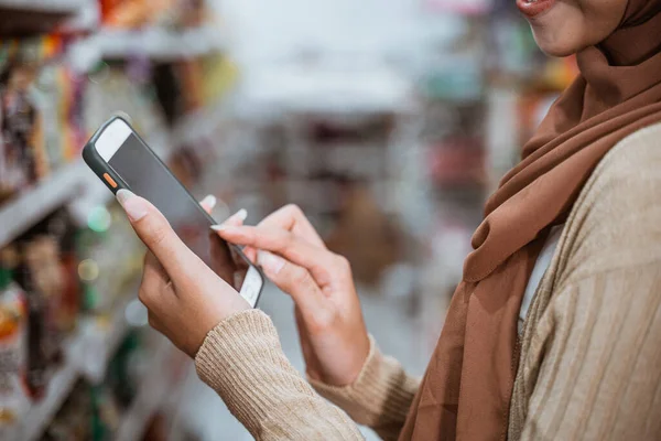 穆斯林妇女在超级市场用手触摸智能手机的屏幕 — 图库照片