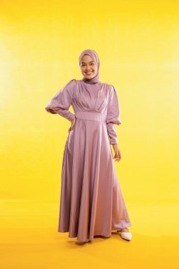 Sarı arka planda elbise giyen neşeli kadın muslimah 'ın vücut ölçüleri tam boy.