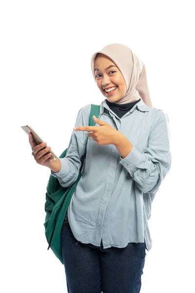 Улыбающаяся Азиатская Студентка Хиджаба Указывающая Мобильный Телефон Белом Фоне — стоковое фото