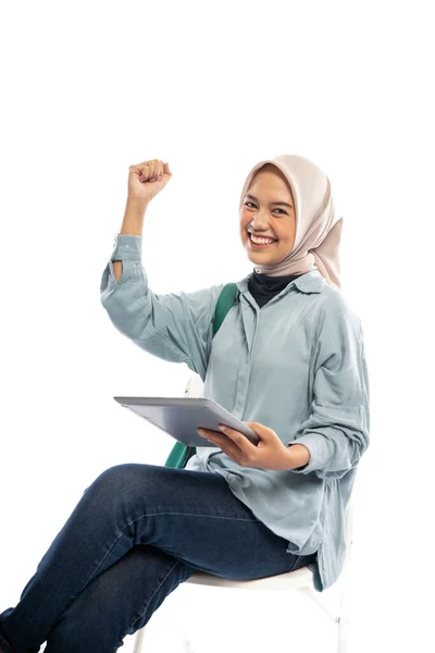 坐在白色背景的数码平板电脑上的兴奋的亚洲穆斯林妇女的肖像 — 图库照片