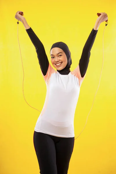 両手でロープをスキップ練習アジアのイスラム教徒の女性は黄色の背景に上昇 — ストック写真