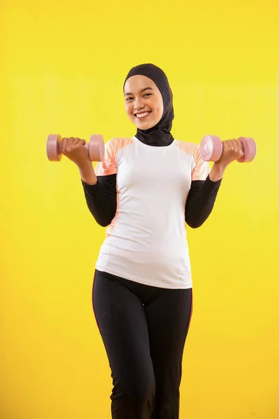 黄色の背景にダンベルを使用して断食中に幸せなイスラム教徒の女性 — ストック写真