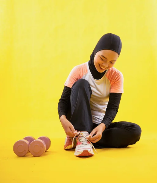 Muslimische Frau Sportkleidung Sitzt Ruhe Und Fixiert Schnürsenkel Auf Gelbem — Stockfoto