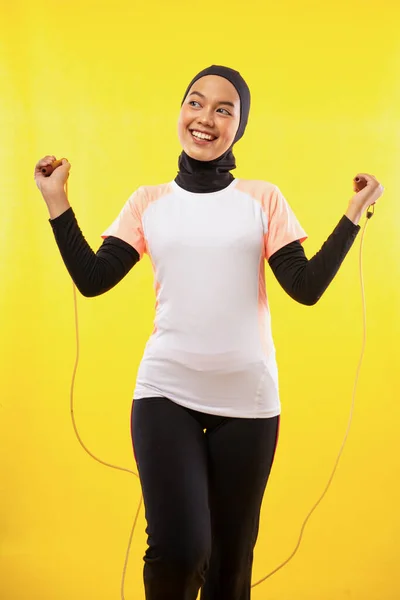 アジア系ムスリム女性が黄色の背景を持つロープをスキップ — ストック写真