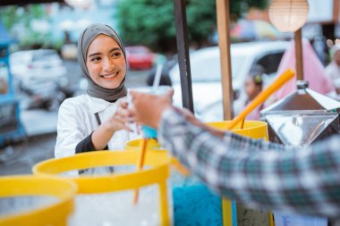 Adam kadın müşterisine renkli içecek ve meyve suyu kavanozunda satıyor. Sokak yemekleri satıcısı.