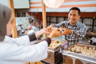 Adam yol kenarında el arabası olan çeşitli hamur köfteleri satıyor.