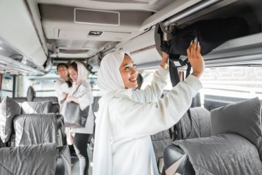 Bayramlarda seyahat ederken başörtülü kadın çantasını otobüs durağına koyar.