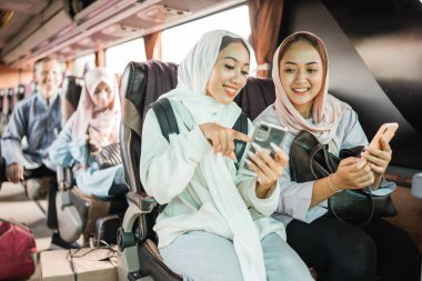 Mübarek bayramında otobüsle seyahat ederken telefon kullanan mutlu Müslüman kadın.