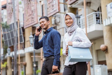 Erkek, sabah kadın Müslüman işçiyle cep telefonuyla işe gider.