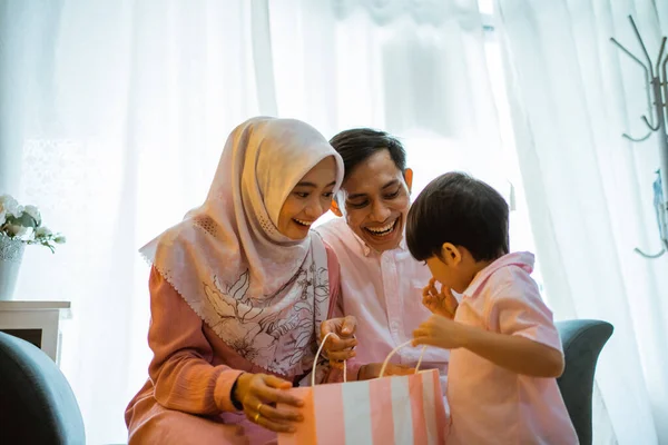 在家庭庆祝活动中 妈妈和儿子打开了爸爸送的纸袋礼物 亚洲穆斯林家庭概念 — 图库照片
