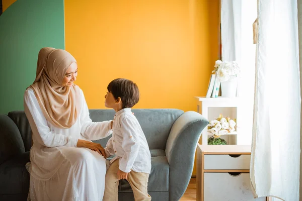 アジアのイスラム教徒のお母さんチャットともに小さな男の子座っていますザソファの上にリビングルーム — ストック写真