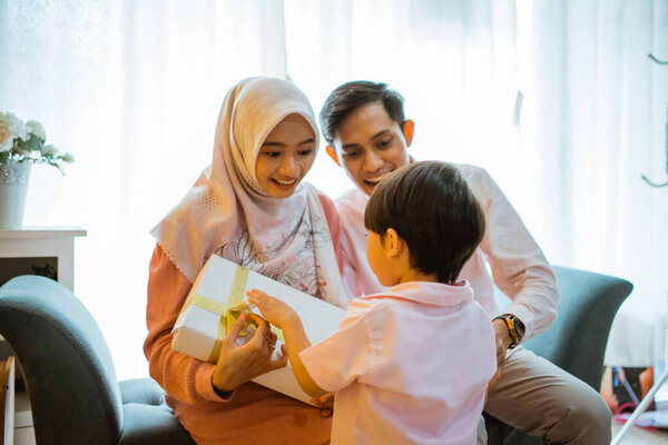 son gives gifts to mom and dad during celebration together at home. Asian Muslim family concept