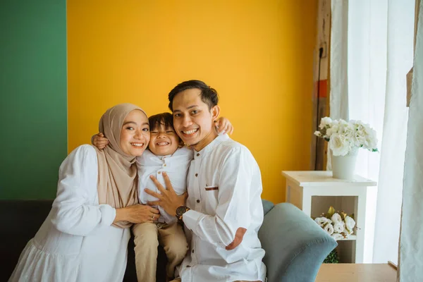 アジア系ムスリムの両親と息子の笑顔の肖像とリビングルームで抱擁 — ストック写真