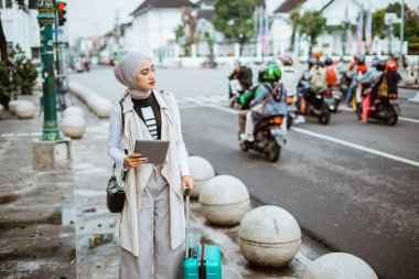 Başörtüsü ile kadın gezgini şaşırt ve kaldırımda dikilirken dijital tableti tut