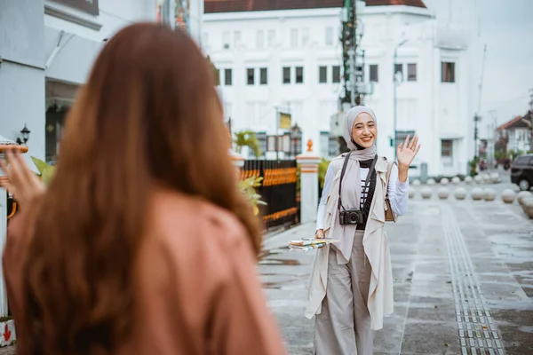 美しいイスラム教徒の旅行者が歩道で顔を合わせながら彼女の友人に手を振って — ストック写真