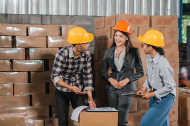 Yönetici ve iki fabrika çalışanı fabrikadaki üretim sahasına yaptıkları ziyarette sohbet ediyorlar.