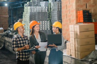 İki kadın ve bir erkek Asyalı fabrika çalışanı fabrikada birlikte çalışırken sohbet ediyorlar.