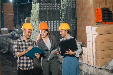 Kadın şirket sahipleri ve fabrika çalışanları fabrikada çalışırken verileri tartışıyor ve inceliyorlar.