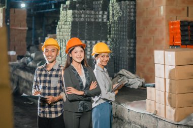 Çekici kadın işadamı ve şirket çalışanı depoda elleri çapraz dururken gülümsüyor.