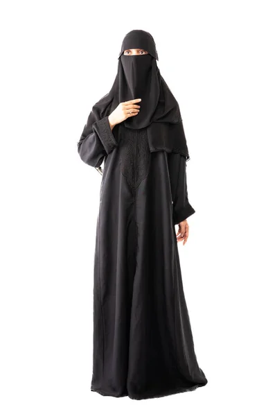 stock image muslim woman wearing a black hijab or niqab and long dress standing in front of white background