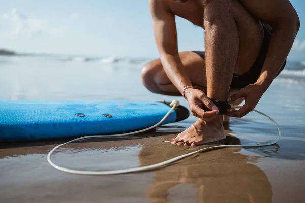一名男子在海滩冲浪前 为了安全起见 把臀部贴在自己的脚上 — 图库照片